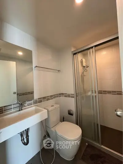 Modern bathroom with sleek fixtures and glass shower enclosure in a contemporary apartment.