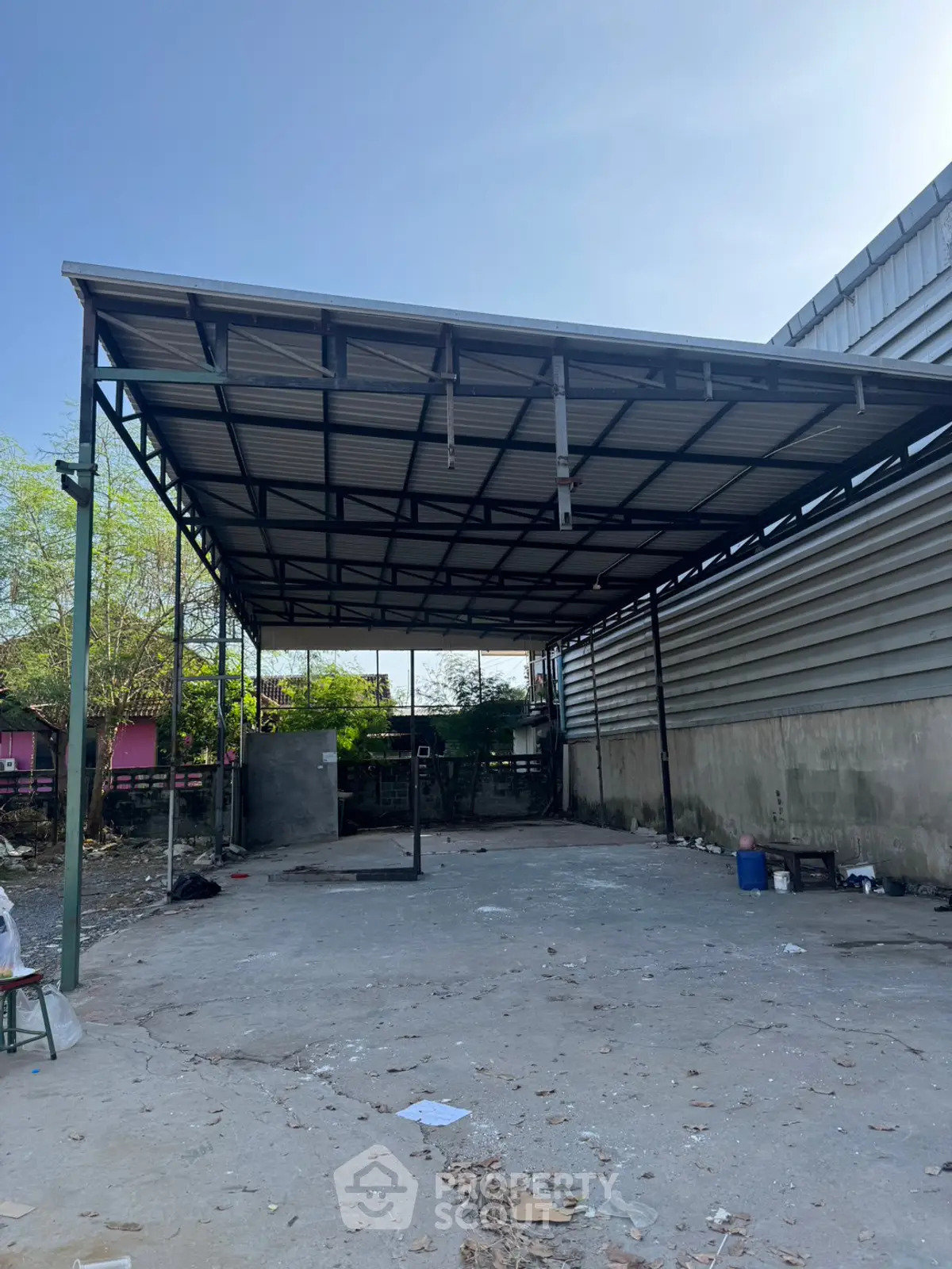 Spacious industrial outdoor area with metal roof and concrete flooring.