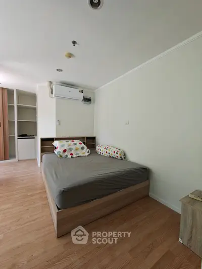 Cozy bedroom with wooden flooring and modern air conditioning unit