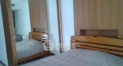 Cozy bedroom with mirrored wardrobe and wooden headboard in modern apartment.