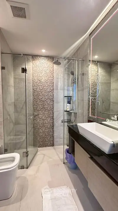 Luxurious modern bathroom with glass shower and elegant vanity in upscale property.