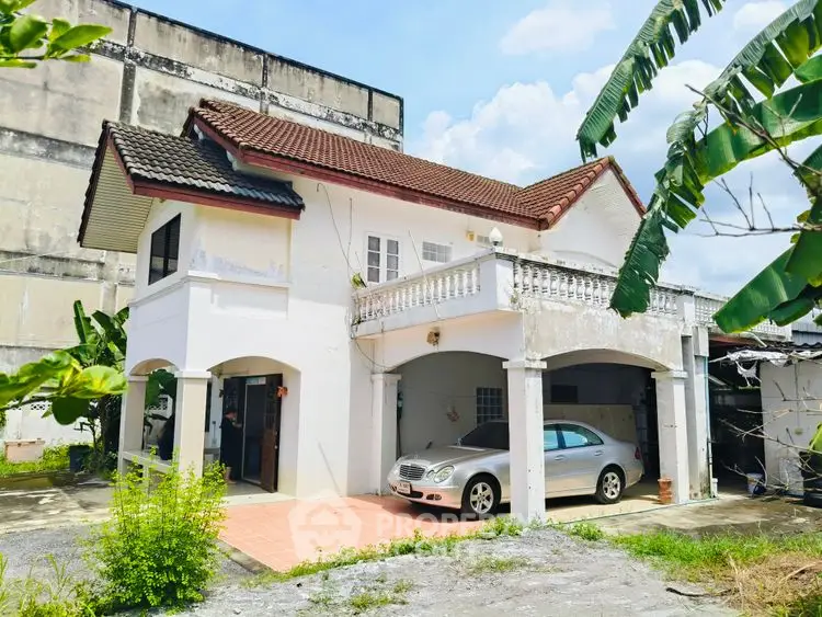 Charming two-story house with carport and lush greenery, ideal for family living.