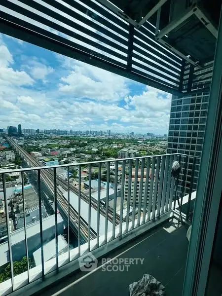 Stunning high-rise balcony view overlooking cityscape with blue skies and clouds.