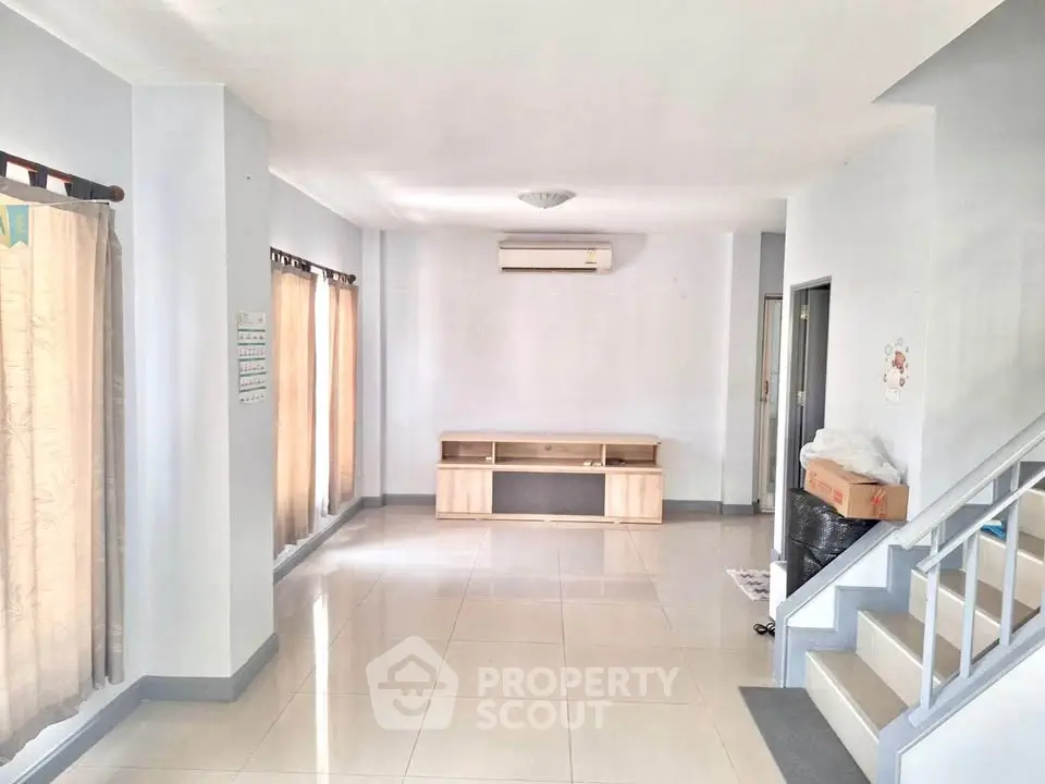 Spacious living room with natural light, tiled floors, and air conditioning, perfect for modern living.