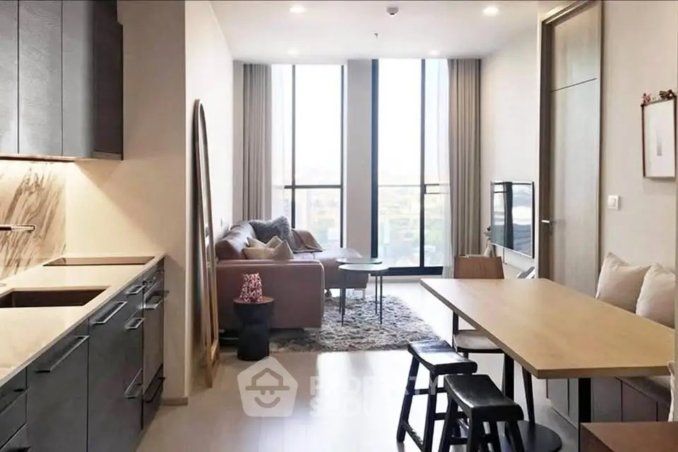 Modern living room with open kitchen, large windows, and stylish decor in a contemporary apartment.