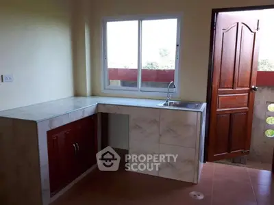 Compact kitchen with marble countertop and wooden cabinets, featuring a single sink and outdoor access.