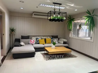 Stylish living room with modern sectional sofa and hanging plants, perfect for relaxation and entertaining.