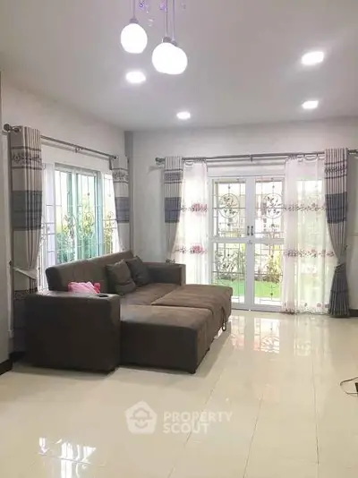 Spacious living room with large windows and modern lighting