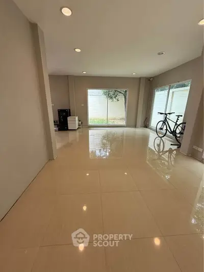 Spacious empty room with large windows and glossy tile flooring, perfect for customization.