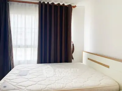 Bright bedroom with large window and elegant curtains, featuring a comfortable mattress.