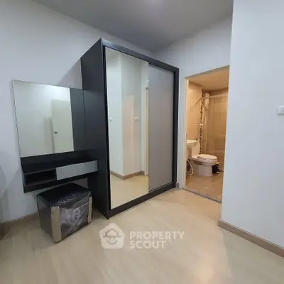 Modern bedroom with sleek wardrobe and ensuite bathroom in a stylish apartment.