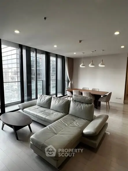 Spacious modern living room with large windows and stylish furniture in a high-rise apartment.