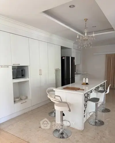 Elegant kitchen with island, chandelier, and modern appliances in a spacious open layout.