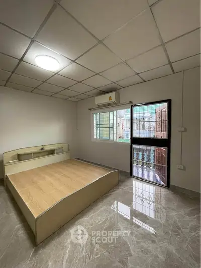 Spacious bedroom with modern design and natural light, featuring a sleek bed frame and glossy tiled flooring.