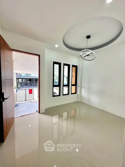 Modern interior with glossy tile flooring and stylish ceiling light, open to a balcony with natural light.