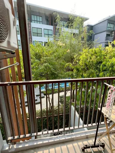 Charming balcony view overlooking lush greenery and modern apartment complex, perfect for relaxation.