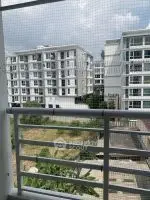 Modern apartment balcony with city view and lush greenery.