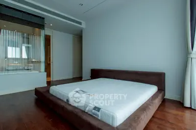 Spacious modern bedroom with minimalist design and large window for natural light.