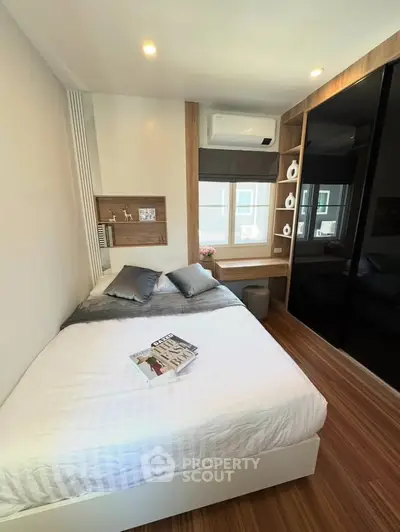 Modern bedroom with stylish decor and wooden flooring, featuring a cozy bed and built-in storage.
