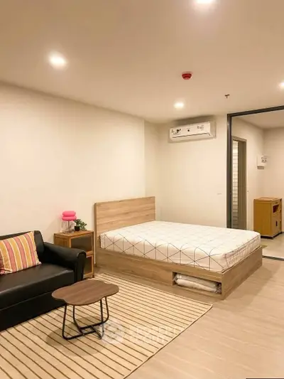 Modern studio apartment with cozy bed, stylish sofa, and sleek wooden flooring.