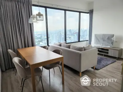 Spacious living room with modern furniture, large windows offering a panoramic city view, and elegant hardwood flooring.