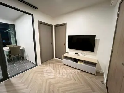 Modern living room with sleek TV setup and access to balcony with dining area.