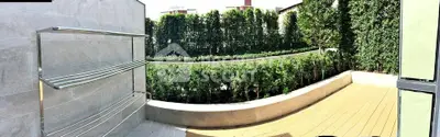 Spacious balcony with lush greenery and modern railing, perfect for relaxation.