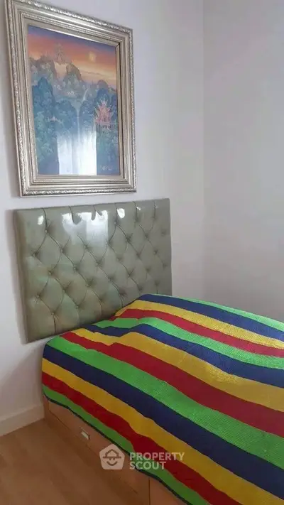 Cozy bedroom with colorful bedspread and elegant framed artwork.