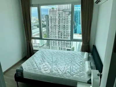Modern bedroom with large window offering stunning city view in high-rise apartment.