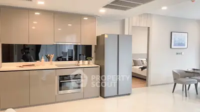 Modern kitchen with sleek cabinets and built-in oven, adjacent to cozy dining area.