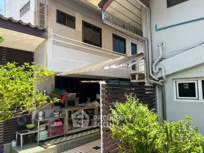 Charming exterior view of a cozy home with lush greenery and practical outdoor kitchen area.