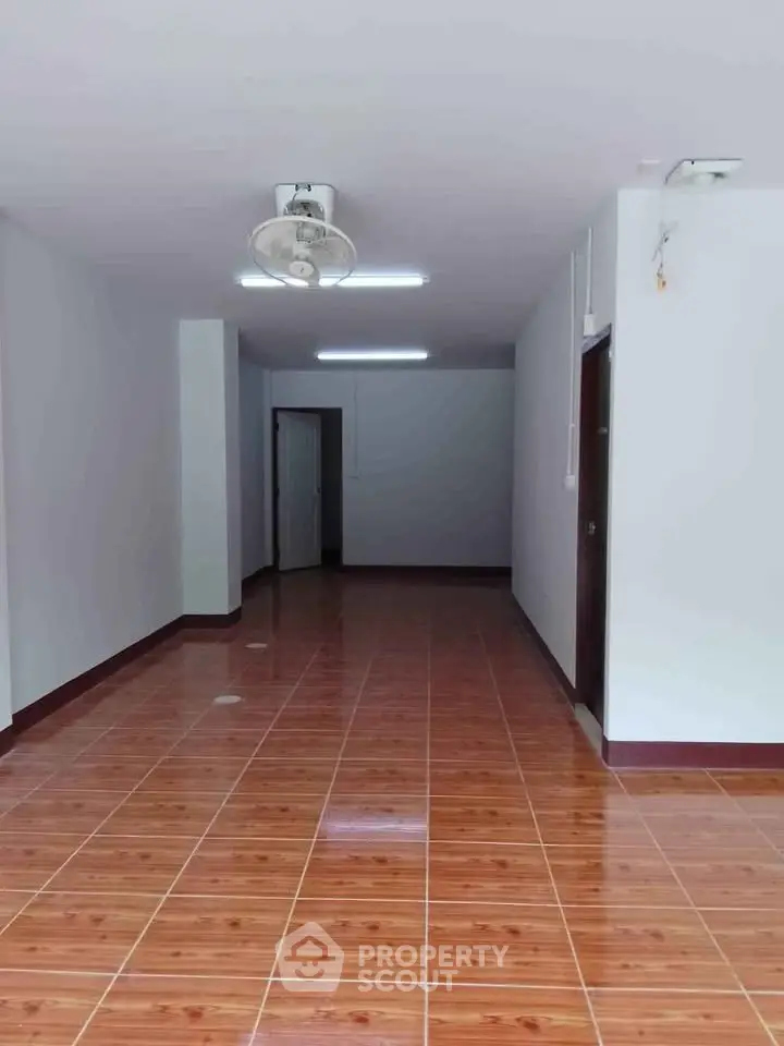 Spacious interior with wooden flooring and ceiling fan, ideal for versatile living space.