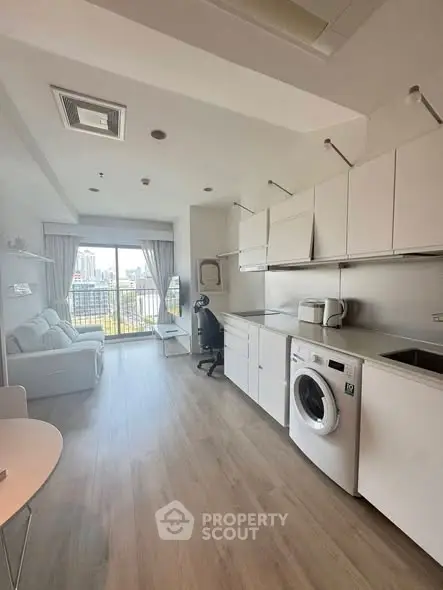 Modern studio apartment with city view, featuring sleek kitchen and cozy living area.