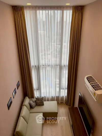 Modern living room with high ceiling and large window, featuring a cozy sofa and wall-mounted TV.