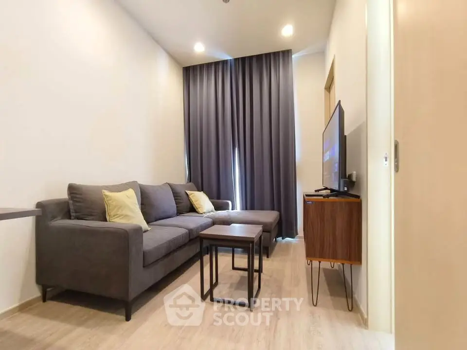 Modern living room with cozy gray sofa and flat-screen TV, perfect for relaxation.