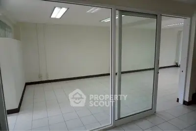 Spacious empty room with tiled flooring and sliding glass doors, ideal for office or studio setup.