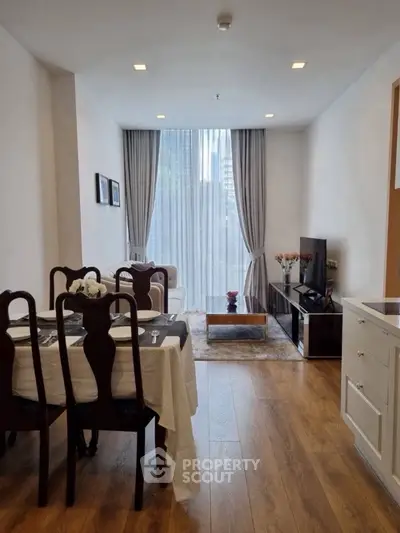 Elegant living room with dining area, wooden flooring, and large window with city view.