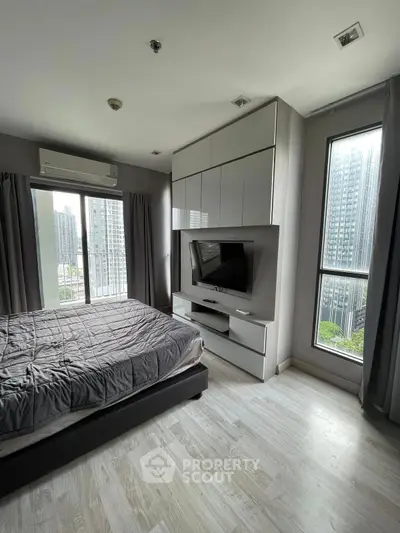 Modern bedroom with large windows and city view, featuring sleek furniture and natural light.
