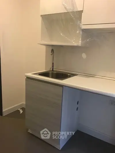 Modern compact kitchen with sleek cabinetry and stainless steel sink in a new apartment.