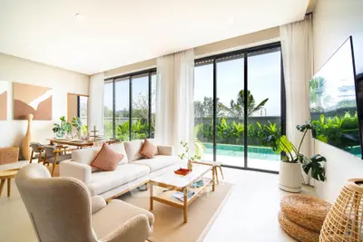 Luxurious living room with pool view, modern furniture, and large windows in a tropical setting.