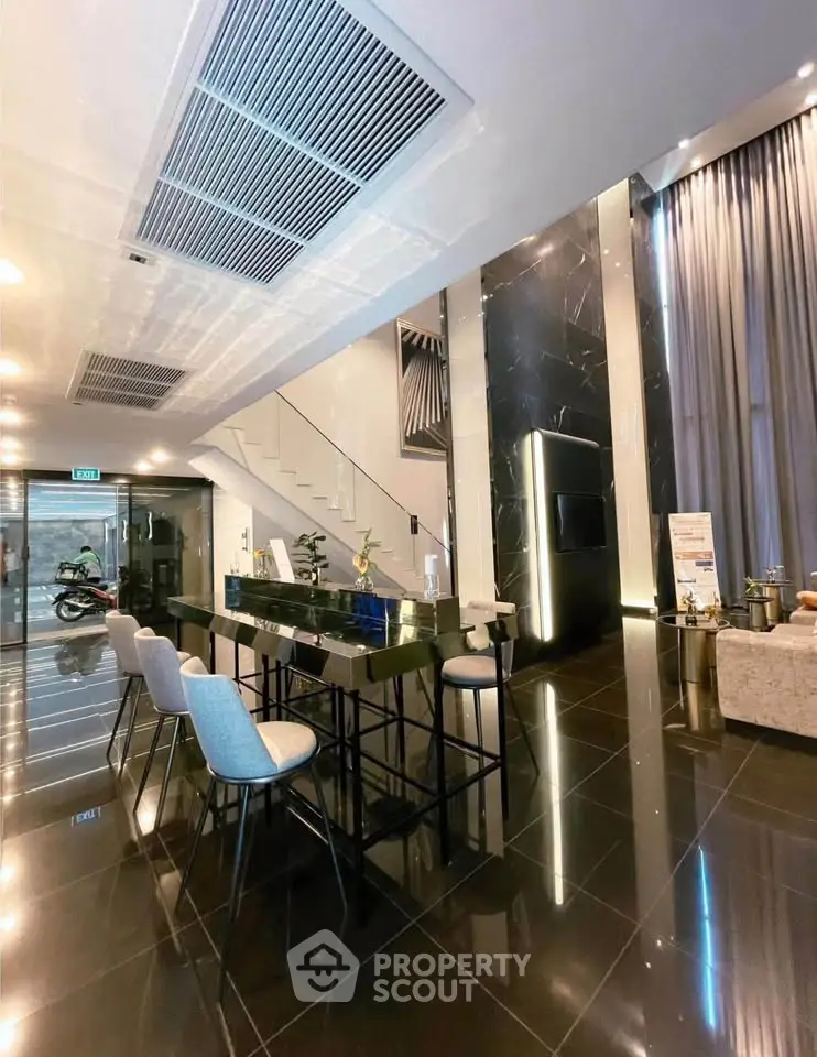 Luxurious modern building entrance with sleek black flooring and stylish seating area.