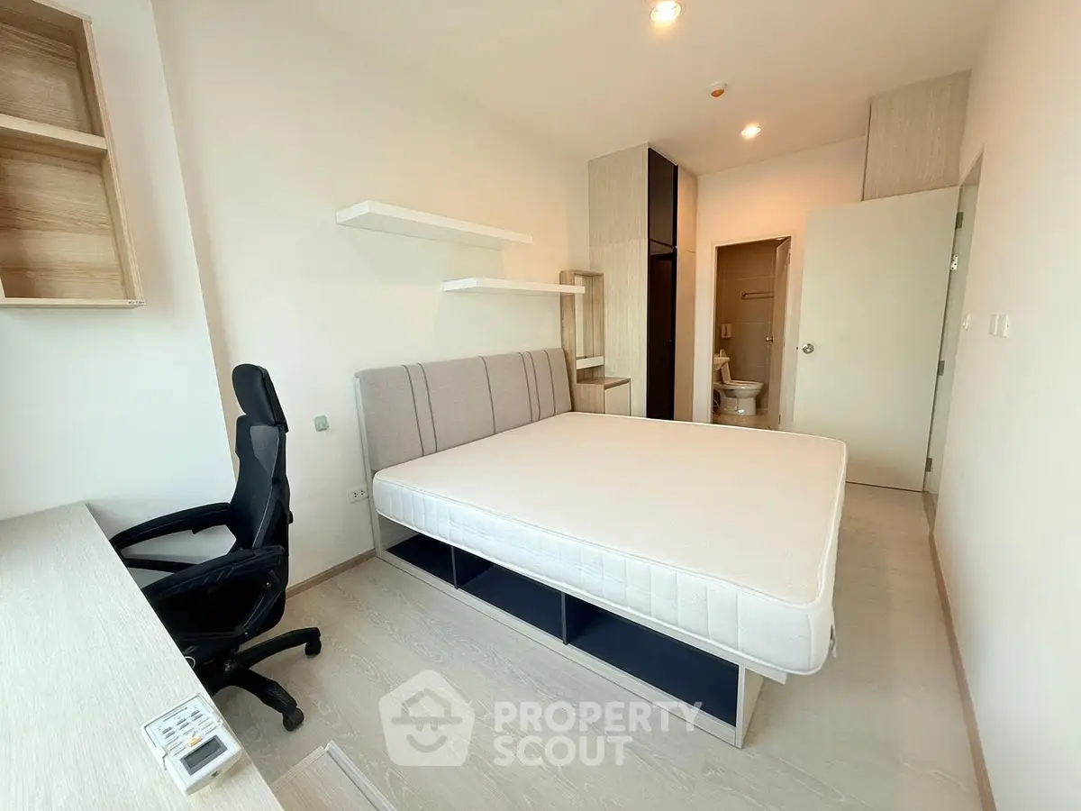 Modern bedroom with minimalist design, featuring a comfortable bed, desk, and chair, ideal for urban living.