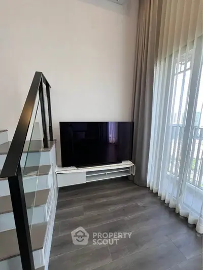 Modern living room with sleek TV setup and elegant staircase