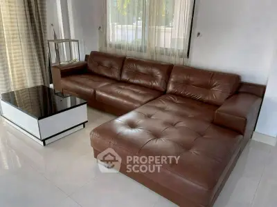 Spacious living room with luxurious brown leather sectional sofa and modern coffee table.