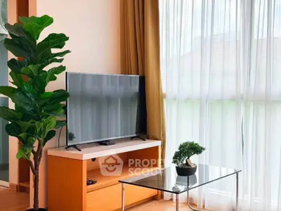 Modern living room with large TV, glass coffee table, and lush indoor plants by a bright window.