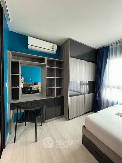 Modern bedroom with built-in wardrobe and stylish desk, featuring natural light and sleek design.
