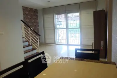 Spacious living room with modern staircase and large windows in a stylish home.