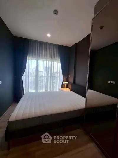 Modern bedroom with large window and elegant dark curtains, featuring a comfortable bed and stylish decor.