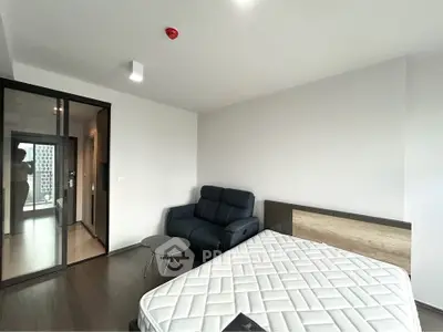 Modern bedroom with sleek design, featuring a cozy sofa and glass partition for a stylish urban living experience.