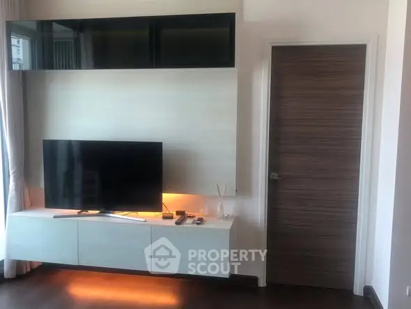 Modern living room with sleek TV setup and stylish wooden door